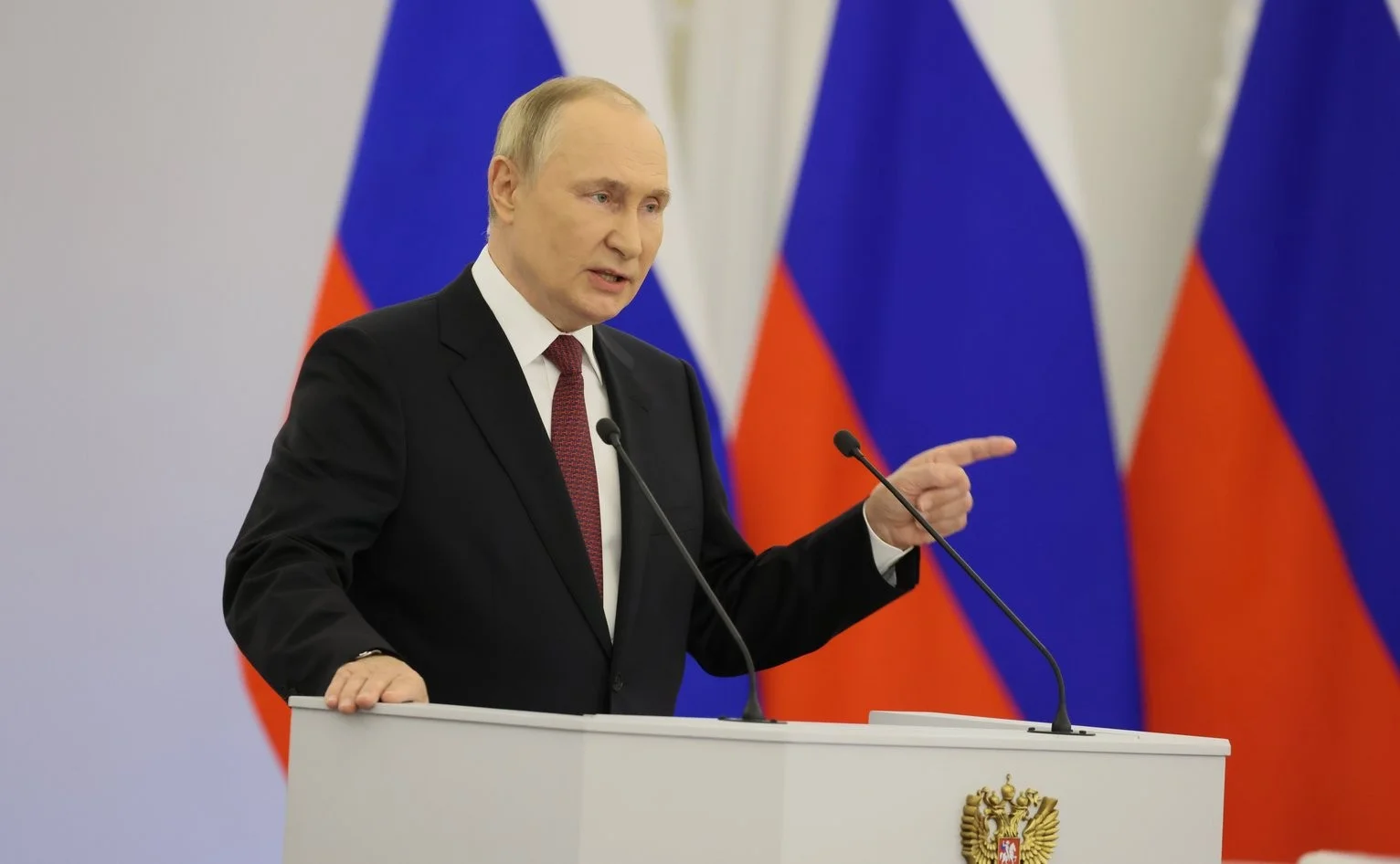 Wladimir Putin während der Rede zur Annexion von ukrainischen Gebieten. Ein ernster Wladimir Putin mit erhobenem Zeigefinger vor drei Russland-Flaggen während der Rede zur Annexion von ukrainischen Gebieten.