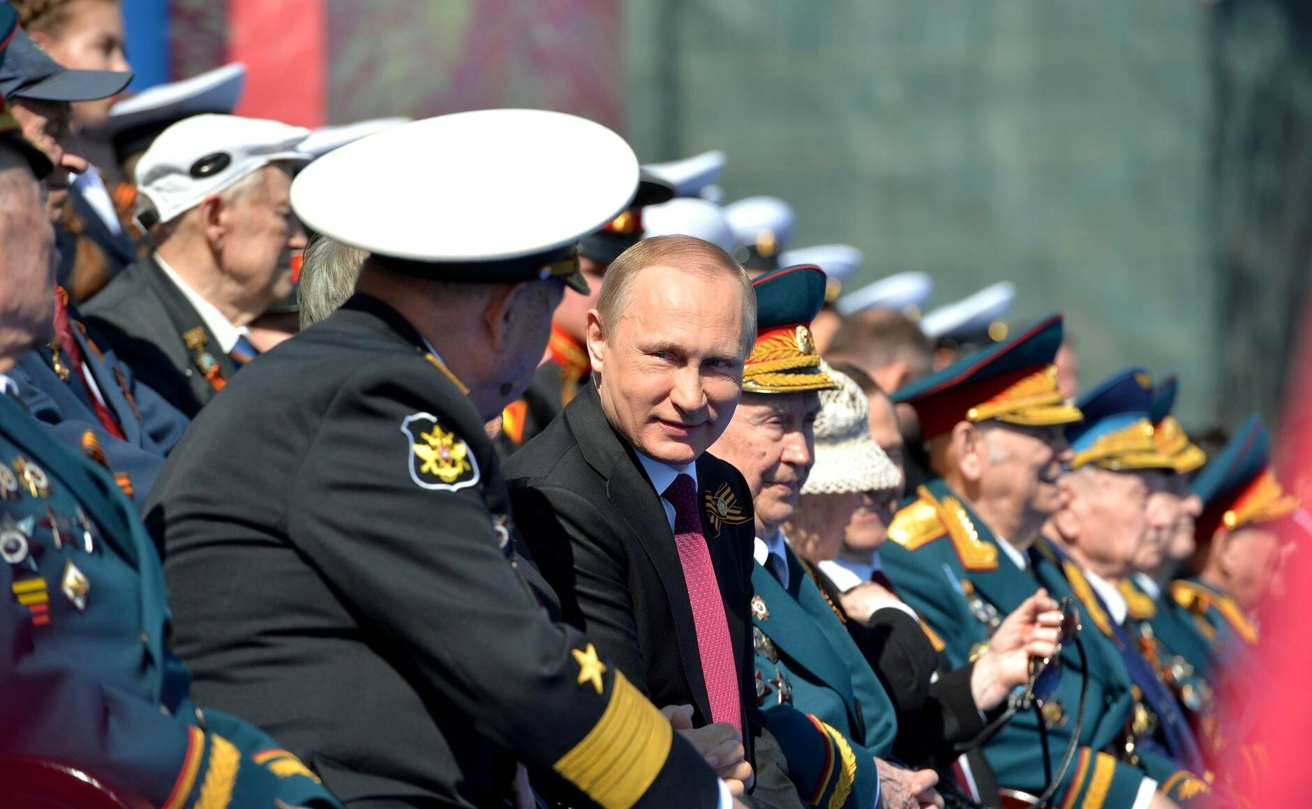 Putin an einer Militärparade, umringt von Generälen.