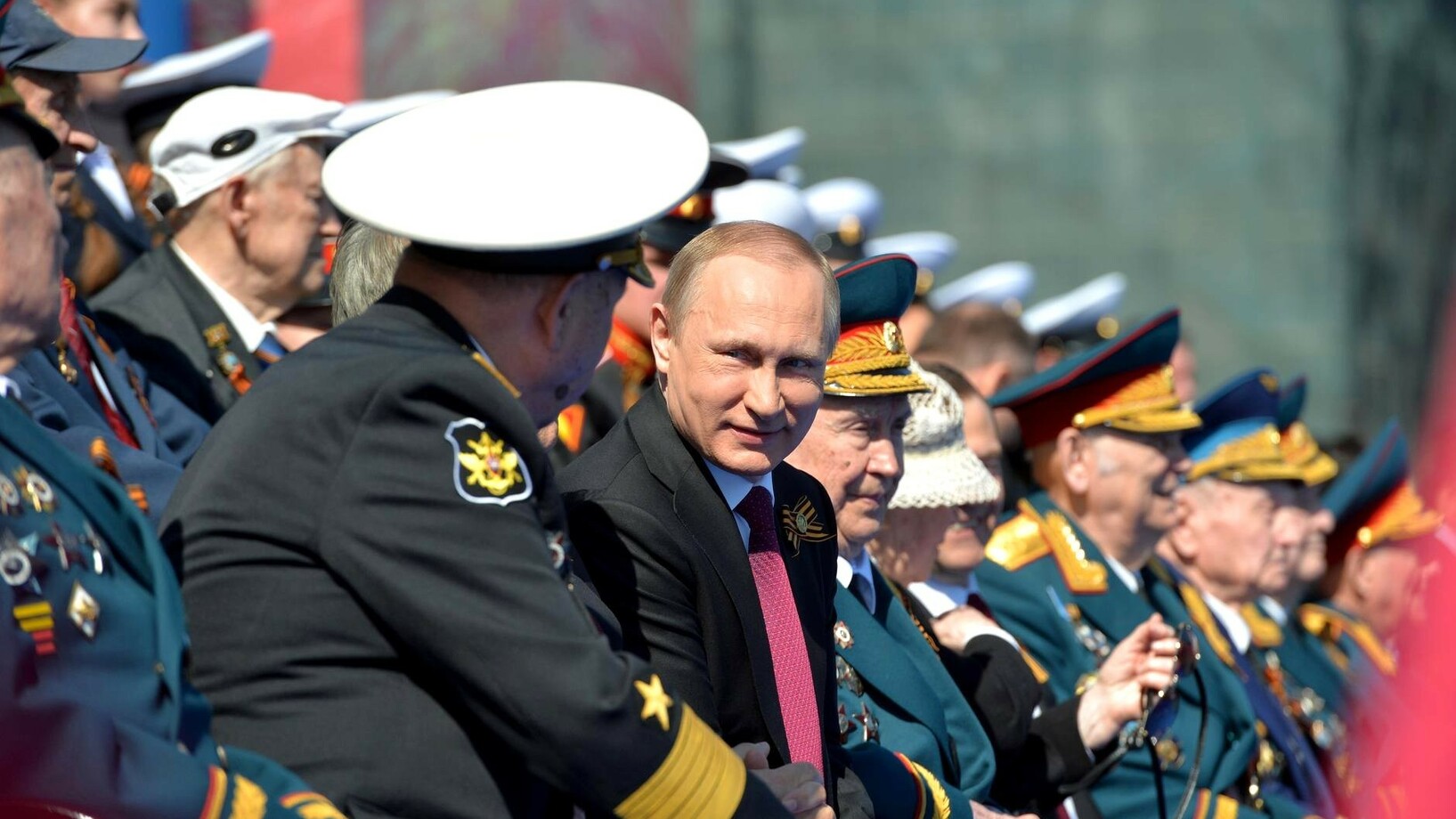 Putin an einer Militärparade, umringt von Generälen.